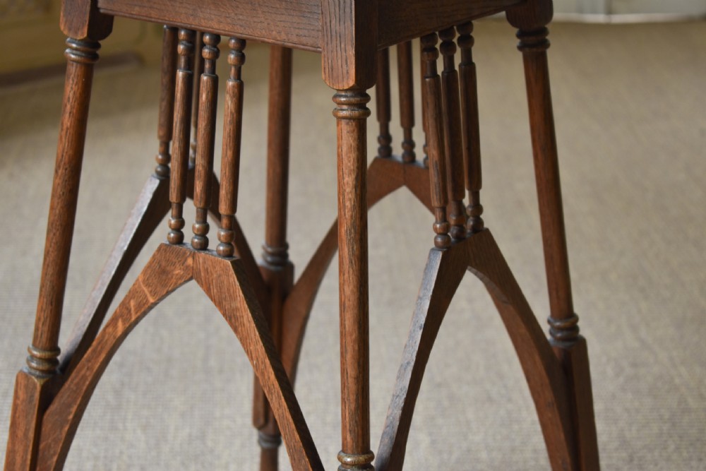 An antique Arts and Crafts oak occasional table featuring a square tiled inset top, arched bracing, and slender turned spindle legs. View IV