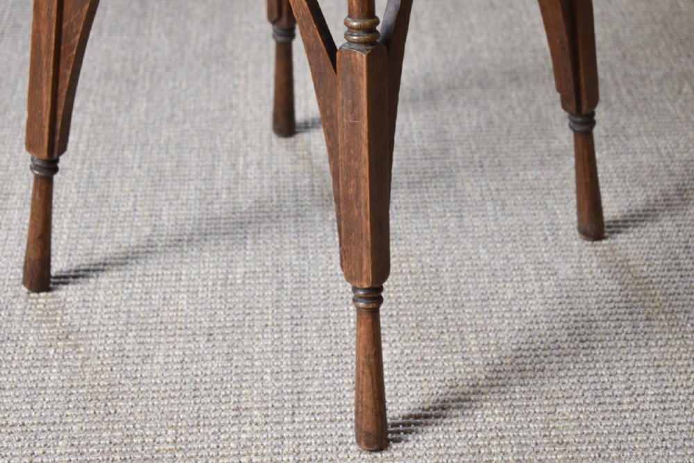 An antique Arts and Crafts oak occasional table featuring a square tiled inset top, arched bracing, and slender turned spindle legs. View V