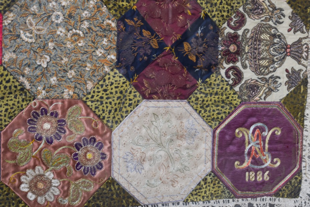 A large square framed Victorian silk patchwork panel featuring octagonal segments with intricate embroidered floral motifs and a dated section in the corner. View III