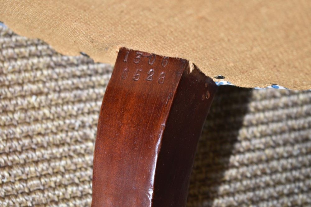 A deep Victorian button-back armchair upholstered in patterned blue and white fabric, set on turned mahogany front legs with brass castors. View VII