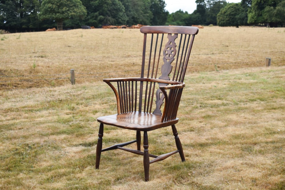 A Victorian dark wood Windsor armchair featuring a high backrest with a wheelback splat, steam-bent armrests, turned legs, and an H-stretcher base.