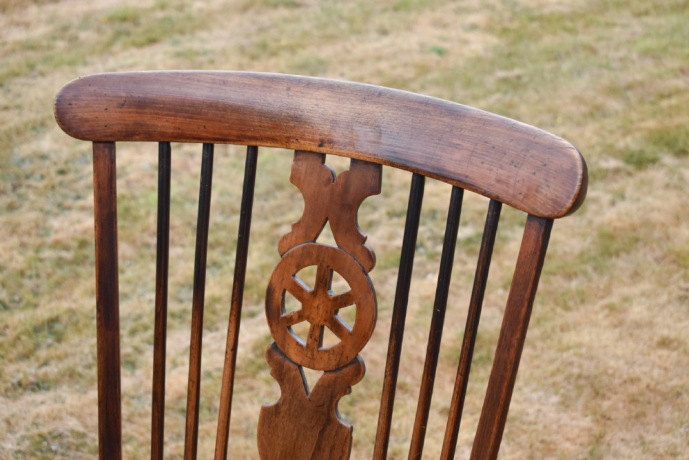 A Victorian dark wood Windsor armchair featuring a high backrest with a wheelback splat, steam-bent armrests, turned legs, and an H-stretcher base. View III