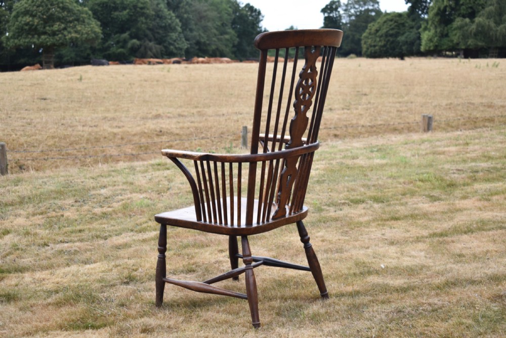 A Victorian dark wood Windsor armchair featuring a high backrest with a wheelback splat, steam-bent armrests, turned legs, and an H-stretcher base. View VI
