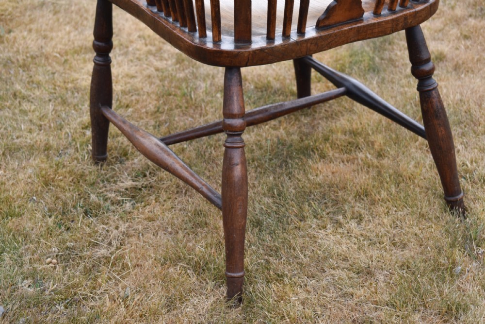 A Victorian dark wood Windsor armchair featuring a high backrest with a wheelback splat, steam-bent armrests, turned legs, and an H-stretcher base. View VII