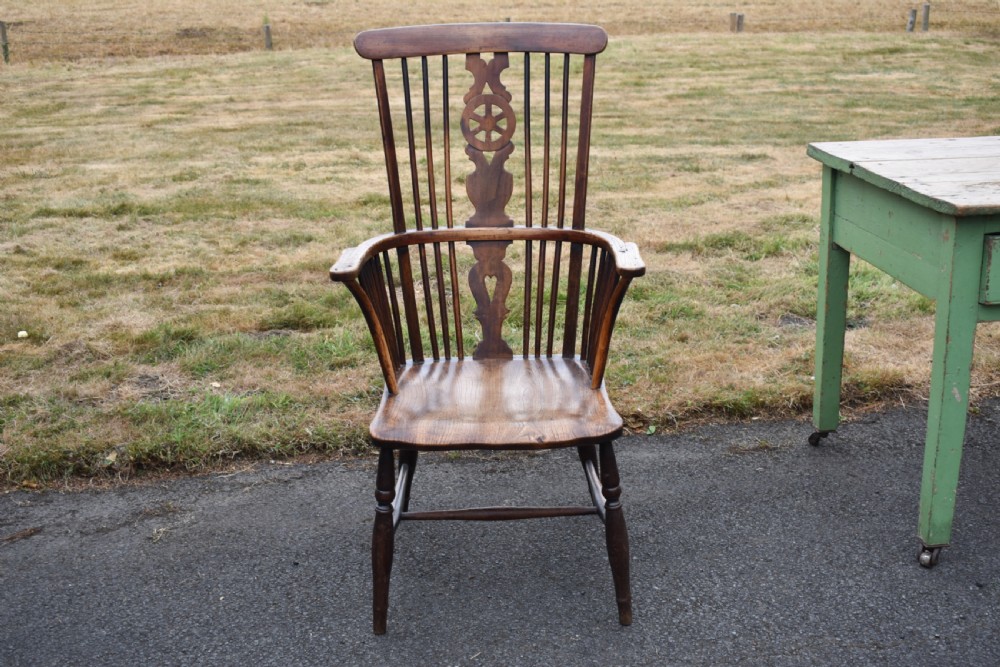 A Victorian dark wood Windsor armchair featuring a high backrest with a wheelback splat, steam-bent armrests, turned legs, and an H-stretcher base. View VIII