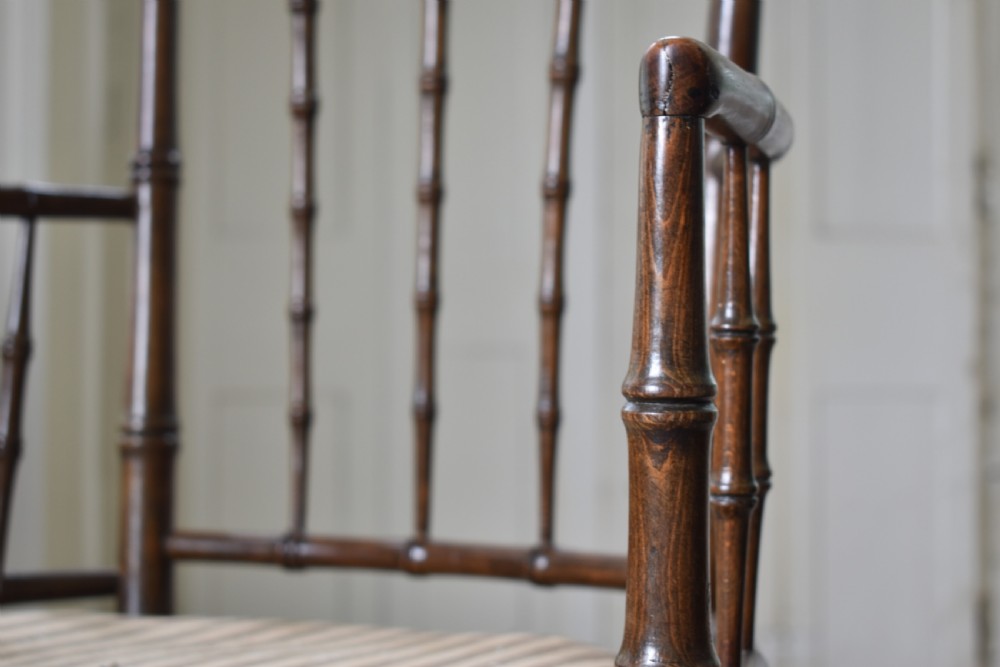 A dark-stained wooden armchair featuring simulated bamboo turnings across the frame and backrest, fitted with a striped fabric seat. View III