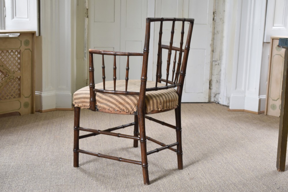 A dark-stained wooden armchair featuring simulated bamboo turnings across the frame and backrest, fitted with a striped fabric seat. View V