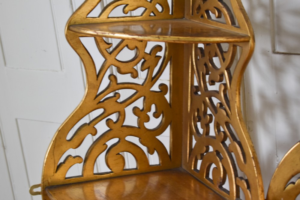A pair of tall Victorian giltwood corner shelves with elaborate pierced fretwork design and multiple tiers. View III