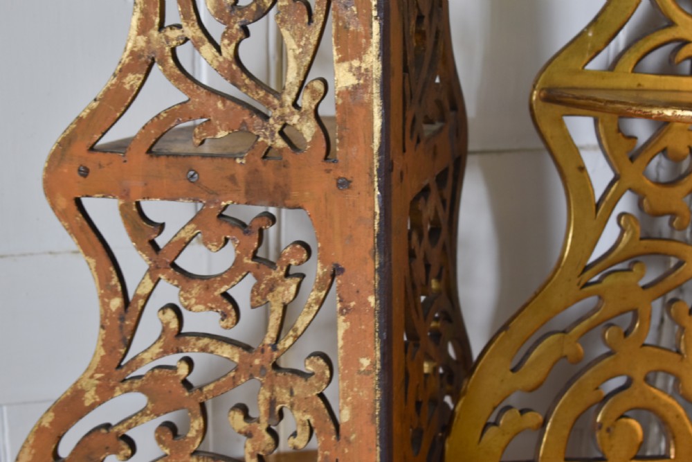 A pair of tall Victorian giltwood corner shelves with elaborate pierced fretwork design and multiple tiers. View IV