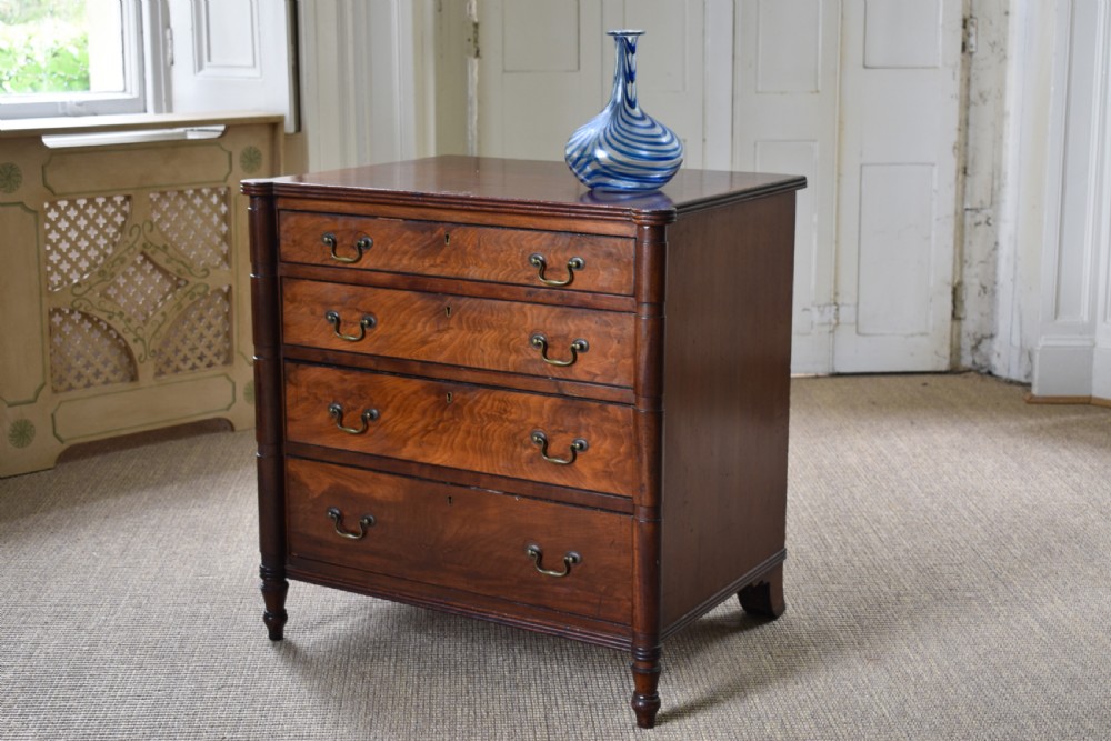 A compact antique mahogany chest of drawers with four graduated drawers, brass handles, and reeded corner details. View III