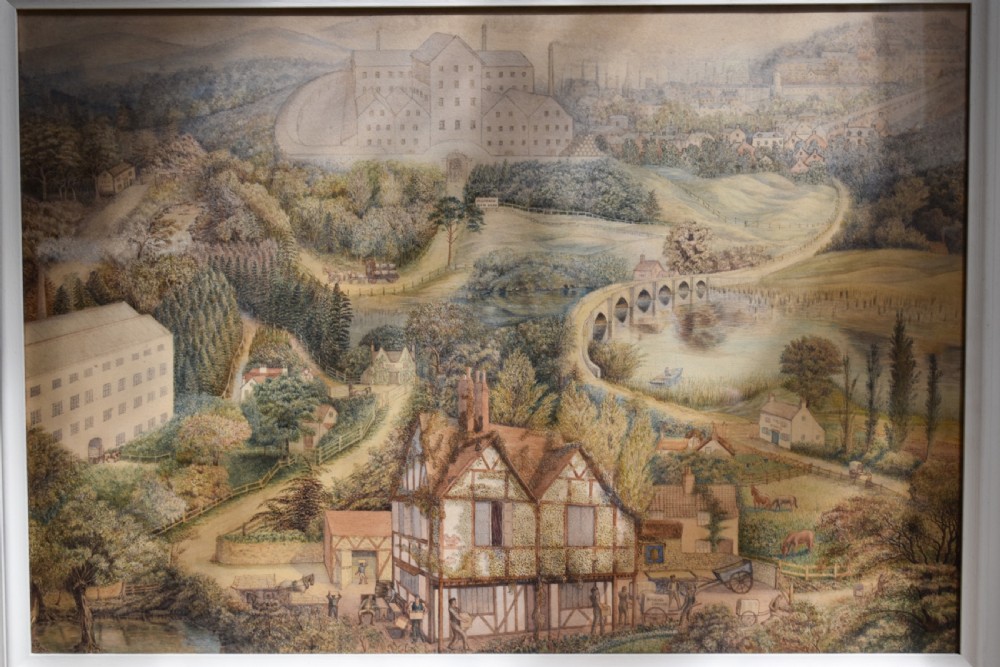 A framed watercolour painting featuring a detailed rural landscape with a brewery, timber-framed building, stone bridge, and rolling green hills. View III
