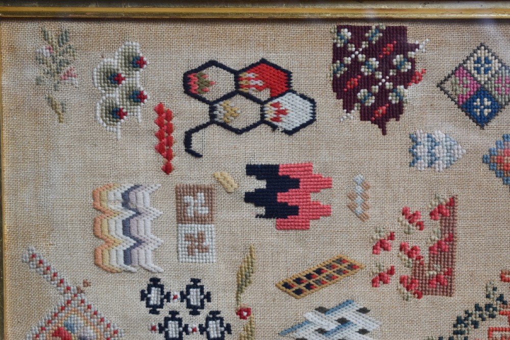 A Victorian framed needlework sampler displaying various geometric cross-stitch motifs on a linen ground within a dark rosewood frame. View II