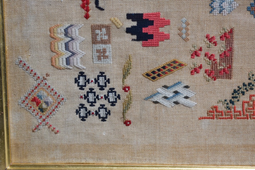 A Victorian framed needlework sampler displaying various geometric cross-stitch motifs on a linen ground within a dark rosewood frame. View III