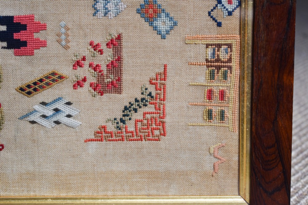 A Victorian framed needlework sampler displaying various geometric cross-stitch motifs on a linen ground within a dark rosewood frame. View IV