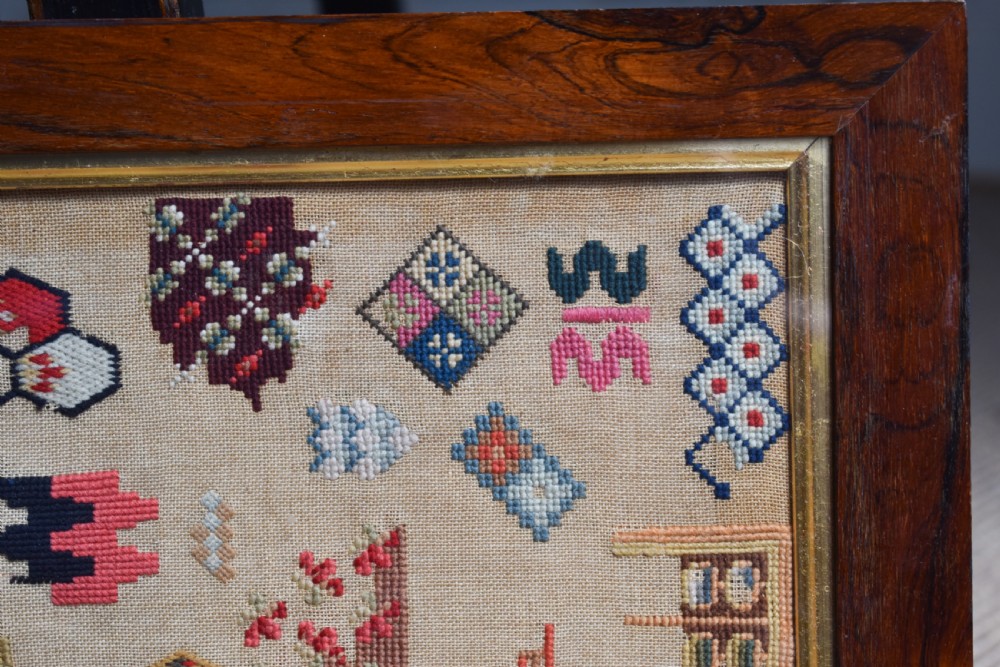 A Victorian framed needlework sampler displaying various geometric cross-stitch motifs on a linen ground within a dark rosewood frame. View V
