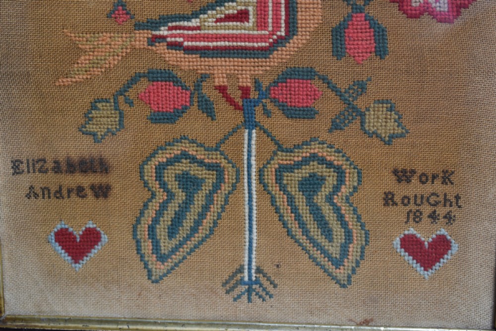 A framed 1844 Victorian needlework sampler featuring an embroidered bird perched on stylized floral stems with hearts and lettering, set in a dark wood frame. View III