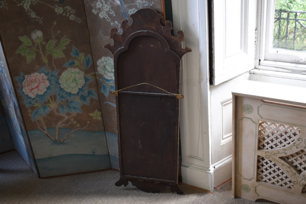 A tall, narrow Queen Anne style mirror featuring an arched frame decorated with chinoiserie hand-painted scenes, a carved gilt shell cresting, and ochre yellow lacquered borders. View VI