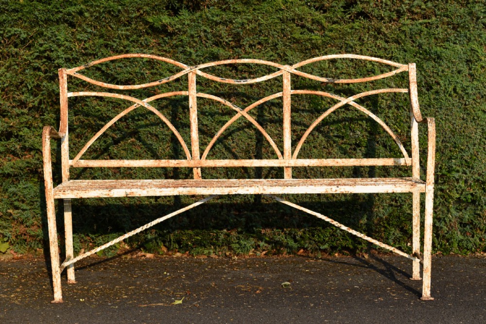 An antique off-white painted wrought iron garden bench featuring arched strapwork back panels and a weathered patina. View VI