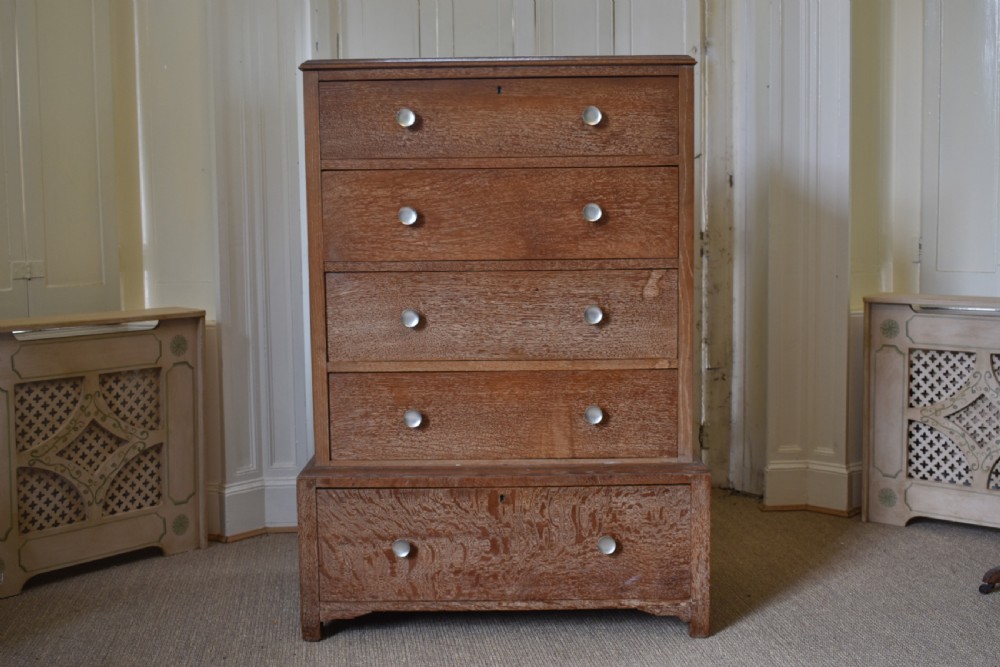 A tall limed oak chest featuring five stacked drawers with small circular turned handles.