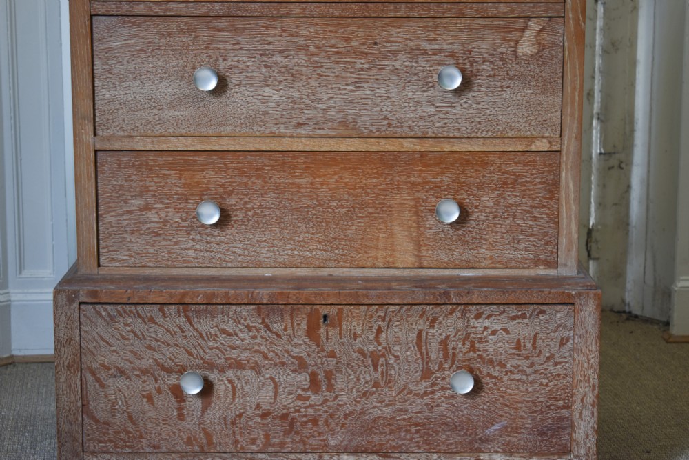 A tall limed oak chest featuring five stacked drawers with small circular turned handles. View II