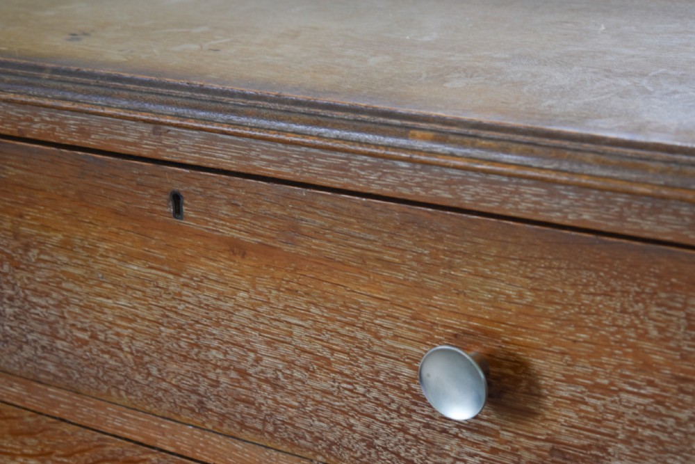 A tall limed oak chest featuring five stacked drawers with small circular turned handles. View III