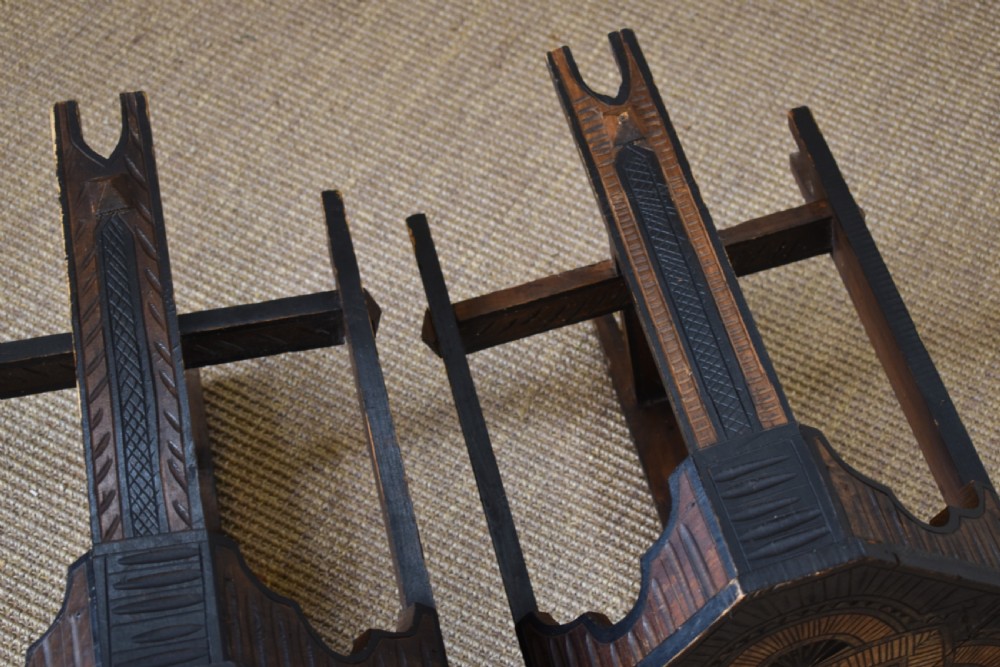A pair of dark stained timber side tables featuring geometric chip-carved star patterns on the tops and carved legs with cross-stretchers. View V