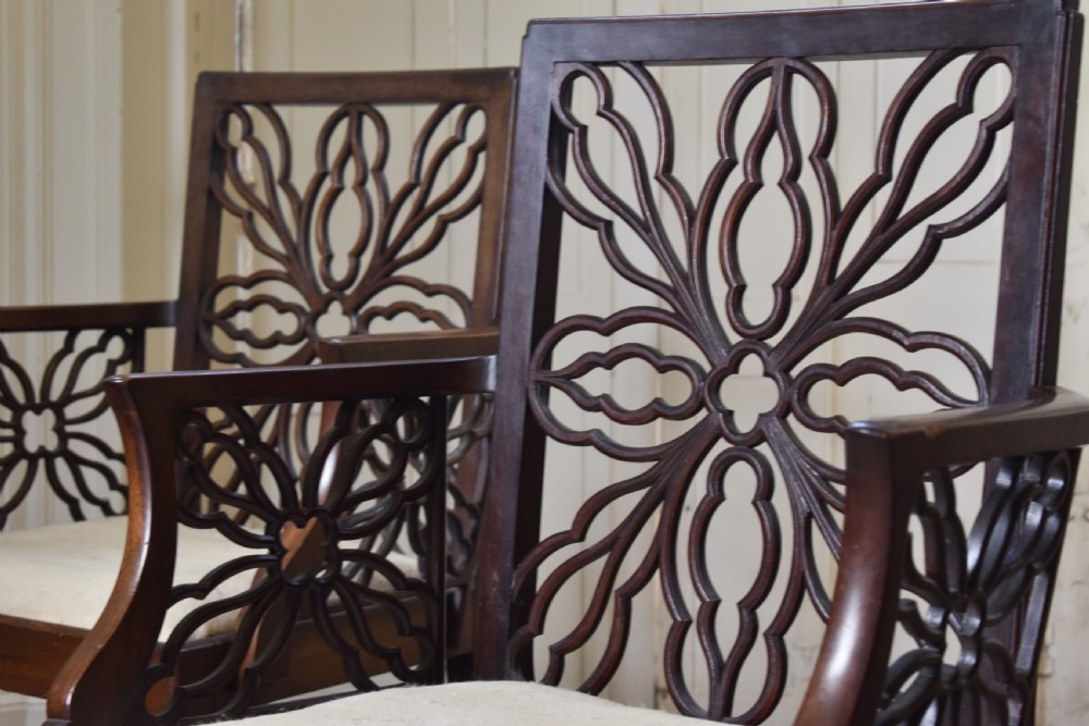 A pair of dark mahogany open armchairs featuring geometric floral fretwork backrests, open carved arms, cream upholstered seats, and cabriole legs with claw and ball feet. View II