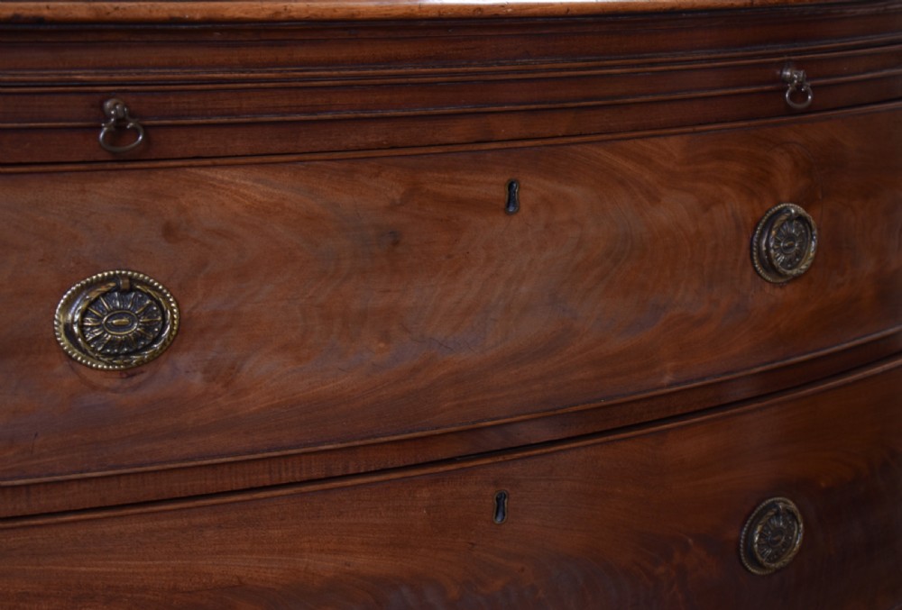 A Georgian flame mahogany bow-front chest of drawers with three open graduated drawers and circular brass handles. View III