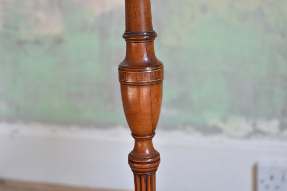 A pair of tall, slender antique satinwood candle stands featuring circular tray tops, fluted turned columns, and circular molded bases. View V