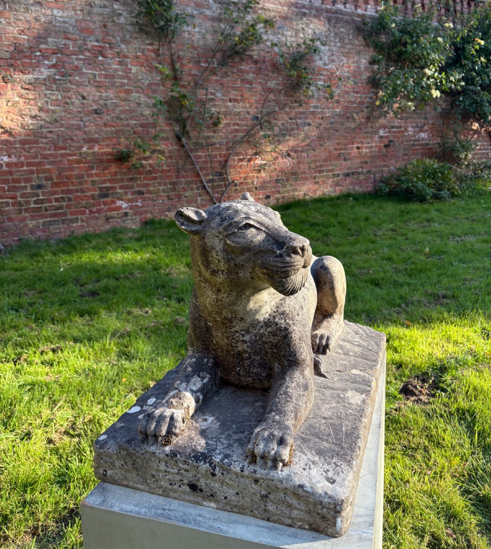 A carved marble sculpture depicting a recumbent lioness resting on an integral rectangular stone base. View II