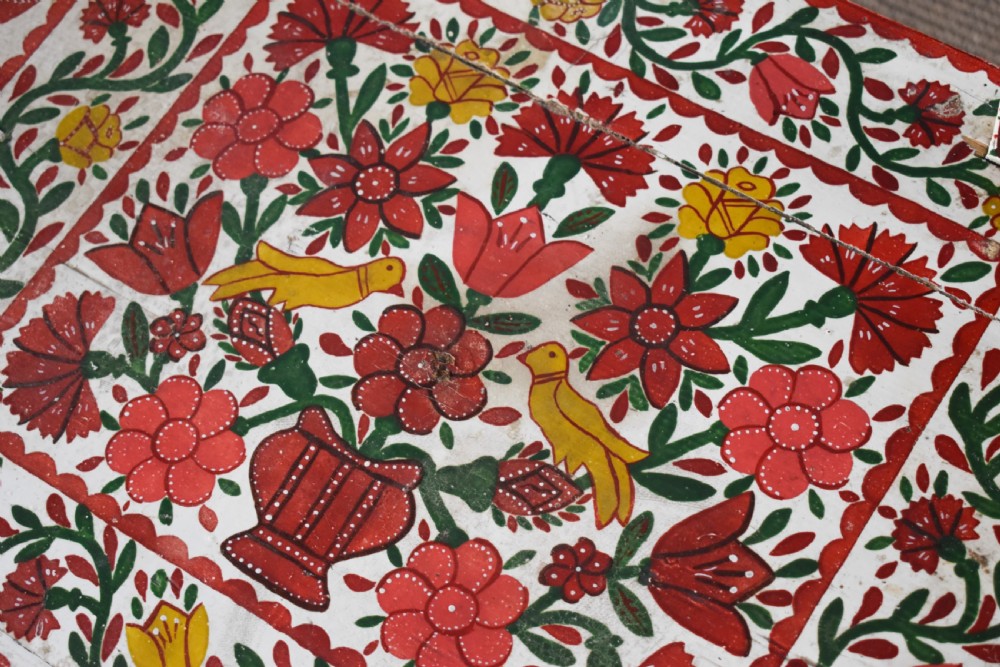 A long hand-painted wooden bench decorated with red, yellow, and green floral patterns across its seat, scalloped backrest, and front apron. View II