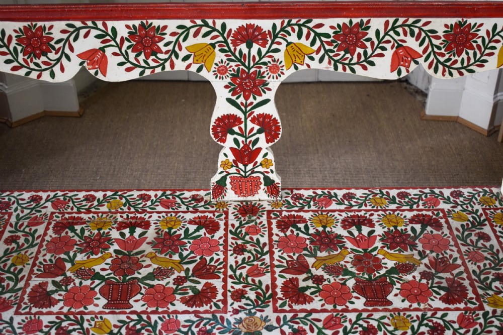 A long hand-painted wooden bench decorated with red, yellow, and green floral patterns across its seat, scalloped backrest, and front apron. View III