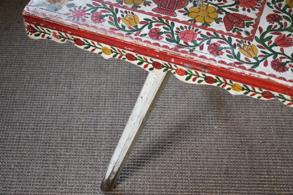 A long hand-painted wooden bench decorated with red, yellow, and green floral patterns across its seat, scalloped backrest, and front apron. View VI