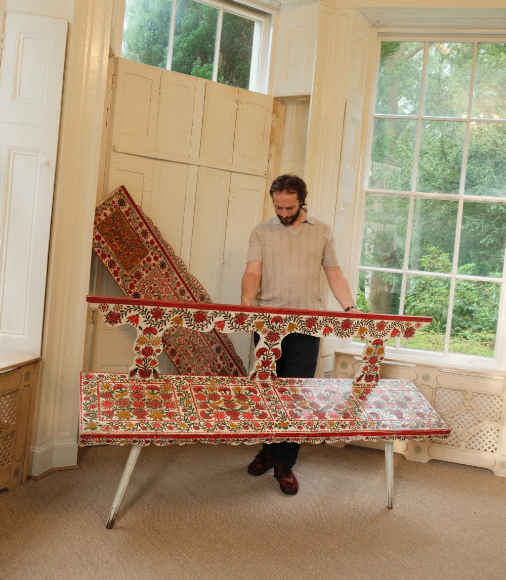 A long hand-painted wooden bench decorated with red, yellow, and green floral patterns across its seat, scalloped backrest, and front apron. View VIII