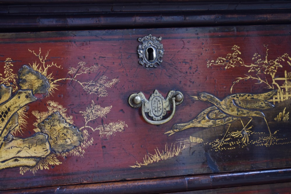 A Georgian red japanned chest of drawers decorated with gilt chinoiserie landscapes and fitted with brass drop handles. View V