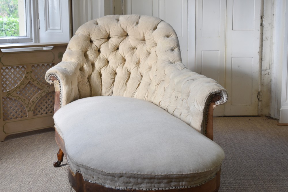 A Victorian upholstered chaise longue with deep-buttoned backrest, carved mahogany frame, and castors on cabriole legs. View IV