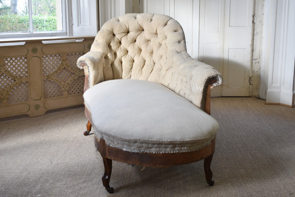 A Victorian upholstered chaise longue with deep-buttoned backrest, carved mahogany frame, and castors on cabriole legs. View V