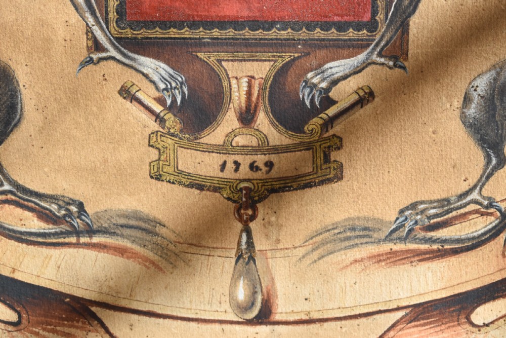 A framed 18th-century heraldic artwork displaying a central coat of arms with anvil motifs flanked by two heraldic griffin supporters. View V