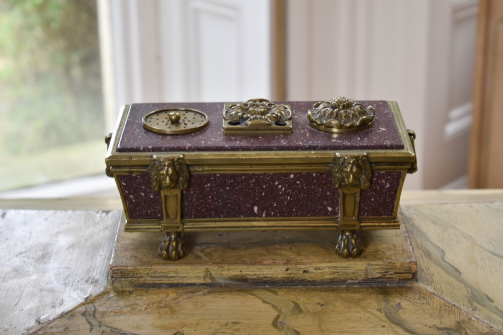 A Regency period sarcophagus-form porphyry inkstand with gilt bronze lion feet, side drop handles, and brass inkwell covers. View II