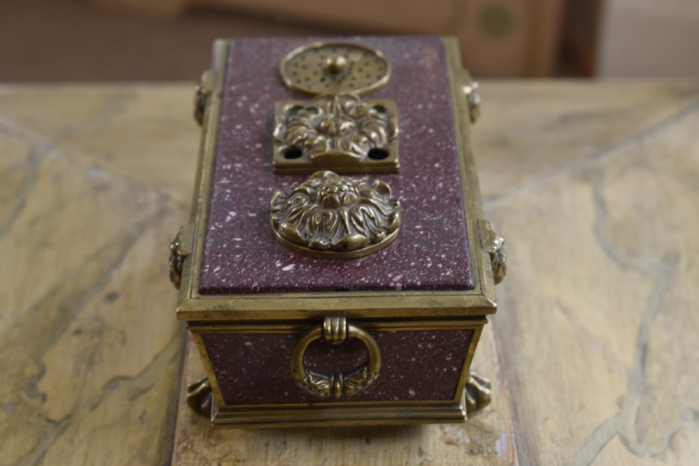 A Regency period sarcophagus-form porphyry inkstand with gilt bronze lion feet, side drop handles, and brass inkwell covers. View IV