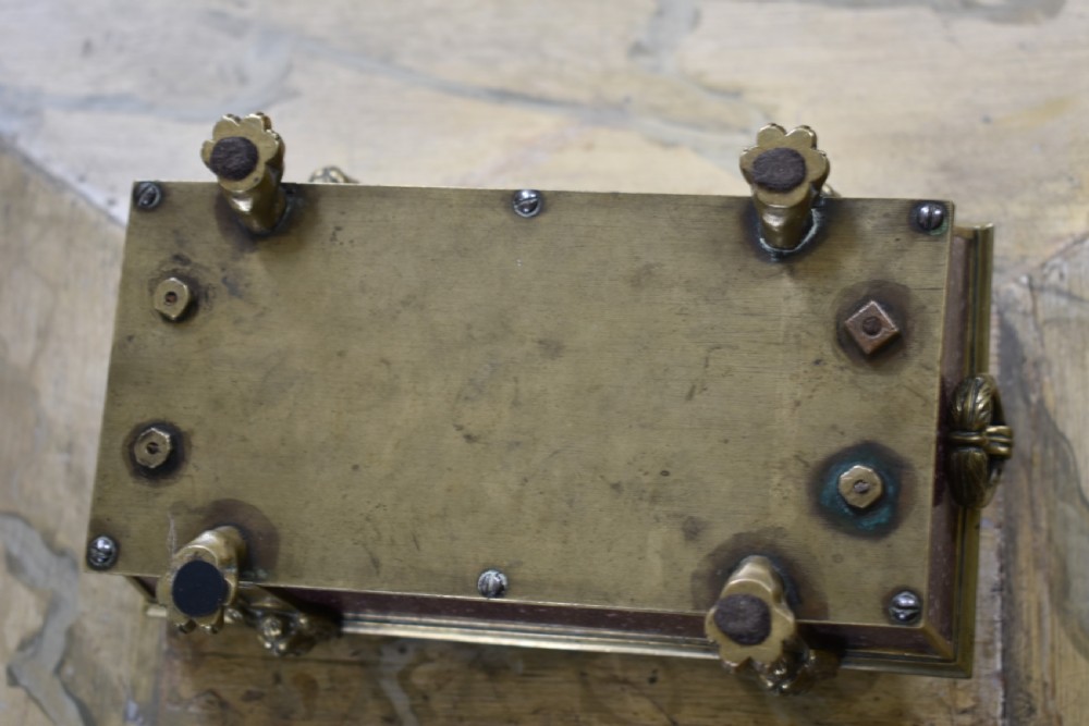 A Regency period sarcophagus-form porphyry inkstand with gilt bronze lion feet, side drop handles, and brass inkwell covers. View VI