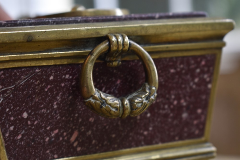 A Regency period sarcophagus-form porphyry inkstand with gilt bronze lion feet, side drop handles, and brass inkwell covers. View VIII