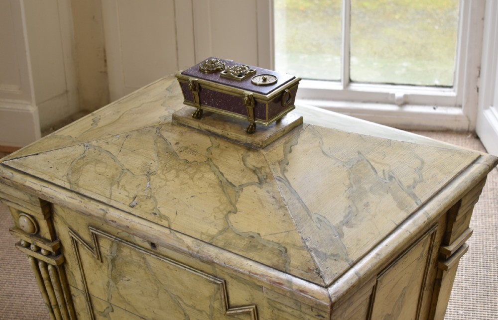 A Regency period sarcophagus-form porphyry inkstand with gilt bronze lion feet, side drop handles, and brass inkwell covers. View IX