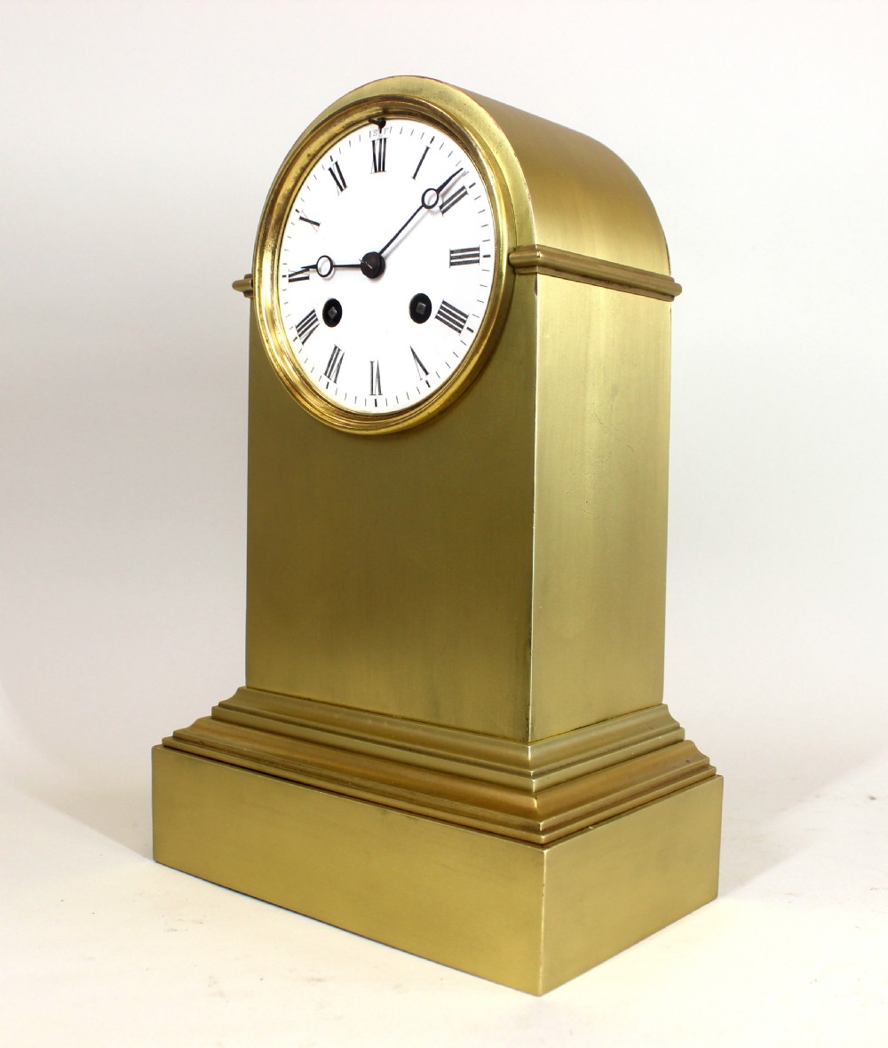 A polished brass dome-topped mantel clock featuring a white enamel dial with Roman numerals on a stepped rectangular base. View III