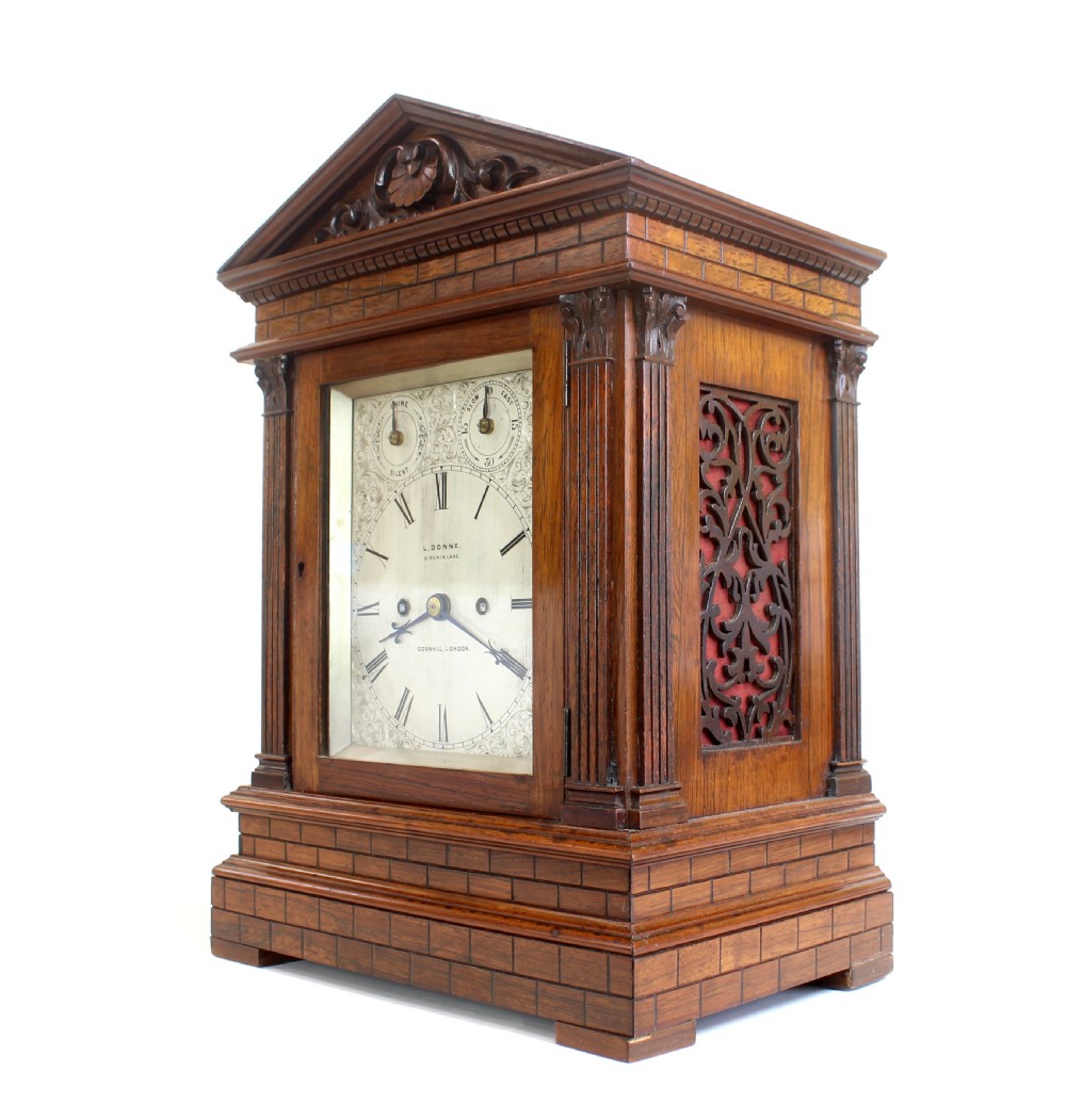 An antique rosewood architectural bracket clock featuring a pediment roof with a carved shell motif, fluted columns, and an engraved silvered dial with Roman numerals. View III