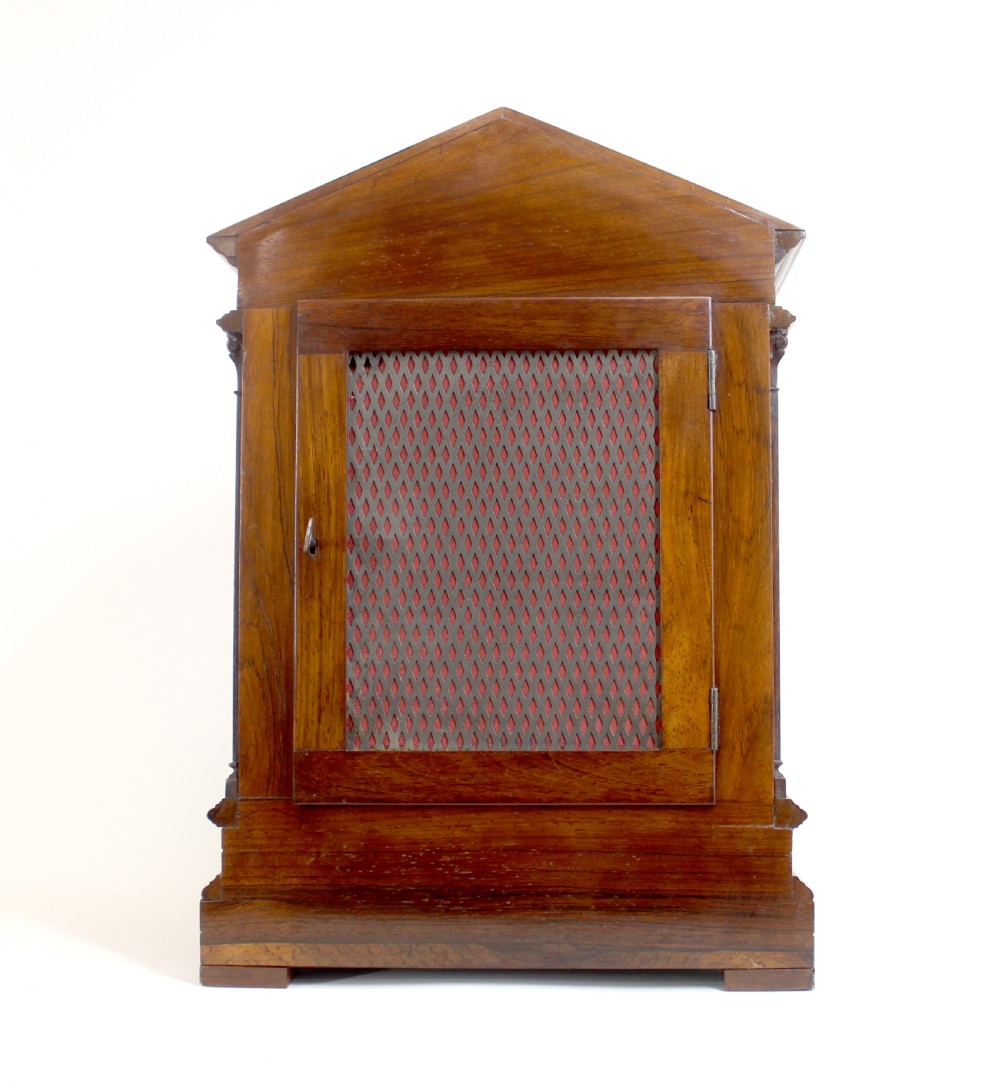 An antique rosewood architectural bracket clock featuring a pediment roof with a carved shell motif, fluted columns, and an engraved silvered dial with Roman numerals. View VII
