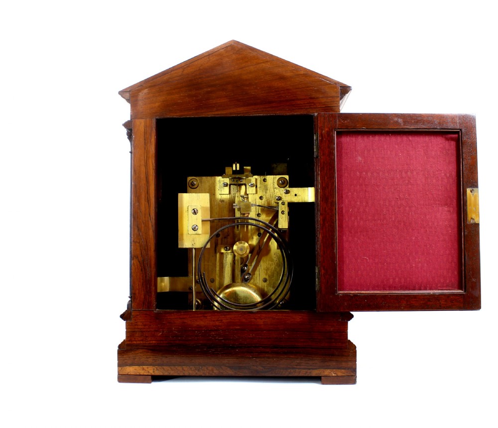 An antique rosewood architectural bracket clock featuring a pediment roof with a carved shell motif, fluted columns, and an engraved silvered dial with Roman numerals. View VIII