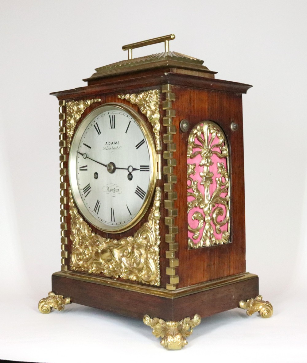 A mahogany and brass bracket clock featuring a white enamel dial with Roman numerals, gilt brass corner mounts, and scroll feet. View III