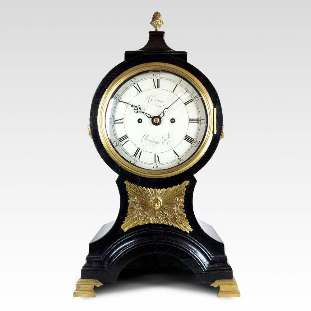 An ebonised balloon mantel clock featuring gilt-brass mounts, a white dial signed Leroux Charing Cross, and brass bracket feet.