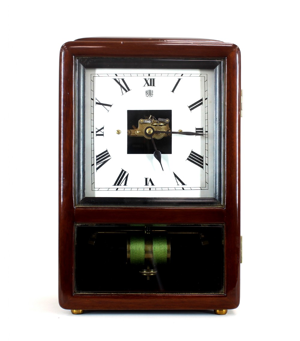 An Art Deco Bulle electric mantel clock featuring a dark mahogany case, white square dial with Roman numerals, exposed movement centre, and visible green electromagnetic coil pendulum.